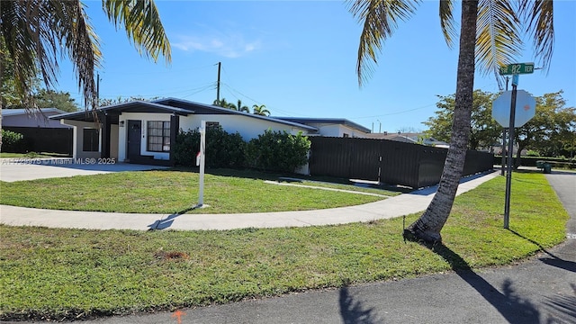 mid-century inspired home with fence, a front lawn, and stucco siding