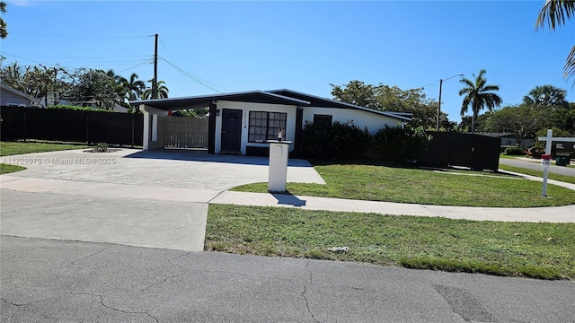 view of front of house with stucco siding, concrete driveway, fence, an attached carport, and a front lawn