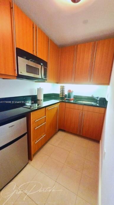 kitchen with stovetop, sink, and light tile patterned floors