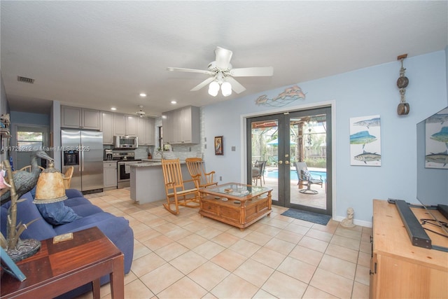 living room featuring light tile patterned floors, visible vents, a healthy amount of sunlight, and a ceiling fan