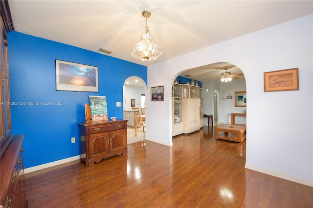 interior space with visible vents, baseboards, wood finished floors, arched walkways, and a ceiling fan