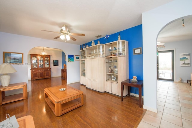 living room with wood finished floors, visible vents, arched walkways, and ceiling fan