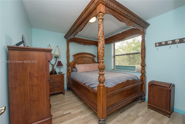 bedroom with a textured ceiling and light wood finished floors