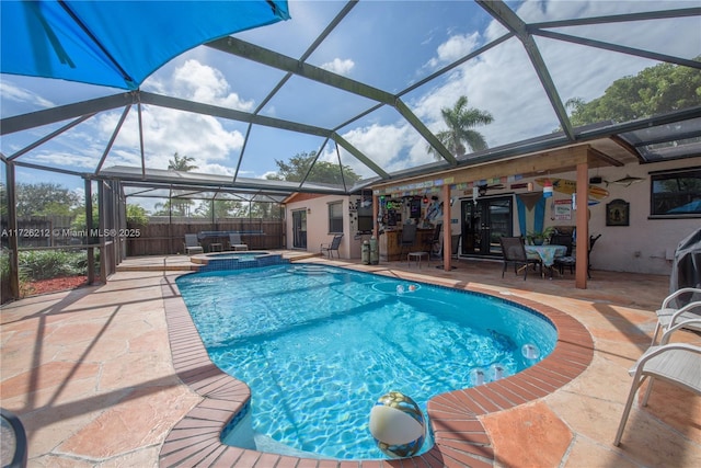 view of swimming pool featuring glass enclosure, a patio, a fenced backyard, and a pool with connected hot tub