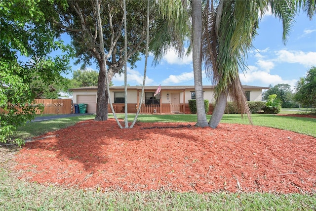 ranch-style home with an attached garage, concrete driveway, a front yard, and fence