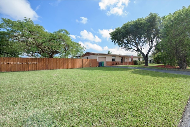 view of yard with aphalt driveway and fence