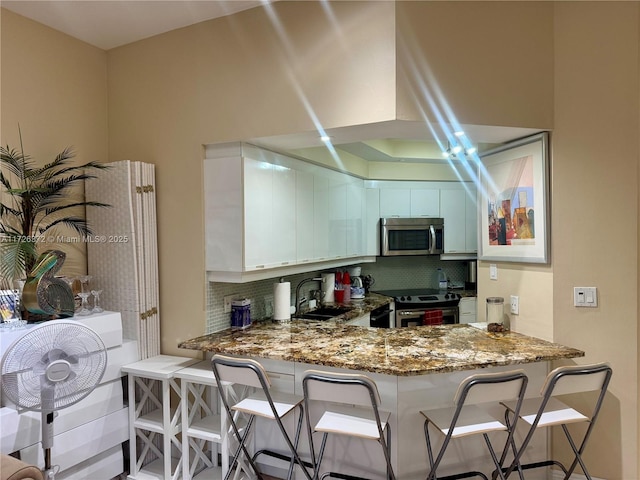 kitchen featuring sink, tasteful backsplash, kitchen peninsula, and stainless steel appliances