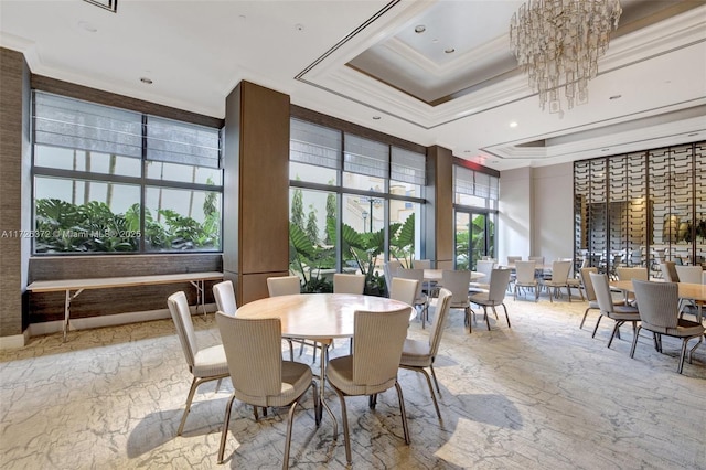 dining space with a tray ceiling, crown molding, a towering ceiling, and an inviting chandelier