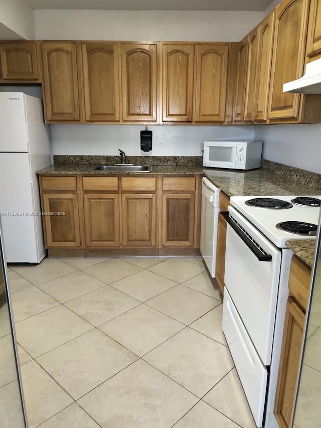 kitchen with sink, white appliances, light tile patterned floors, and dark stone counters