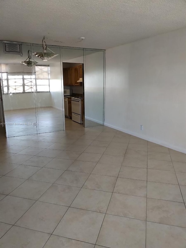 tiled empty room with a textured ceiling