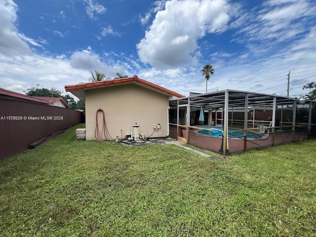 back of house with a fenced in pool, a lanai, and a lawn