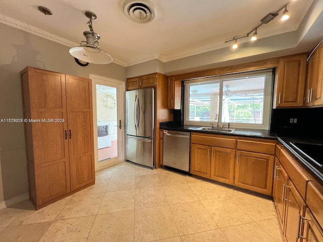 kitchen with appliances with stainless steel finishes, washer / dryer, sink, ornamental molding, and light tile patterned flooring