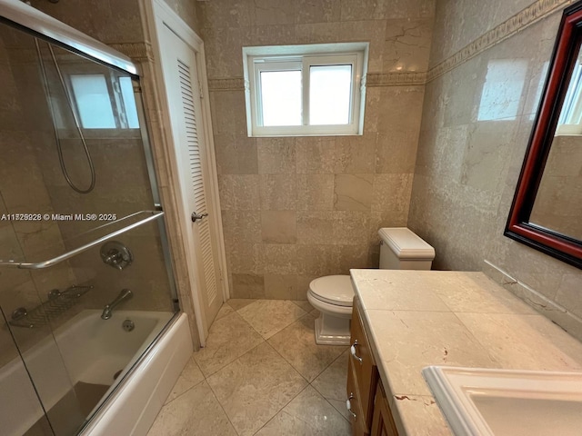 full bathroom with enclosed tub / shower combo, tile patterned floors, vanity, tile walls, and toilet