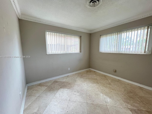 tiled empty room featuring ornamental molding and a textured ceiling