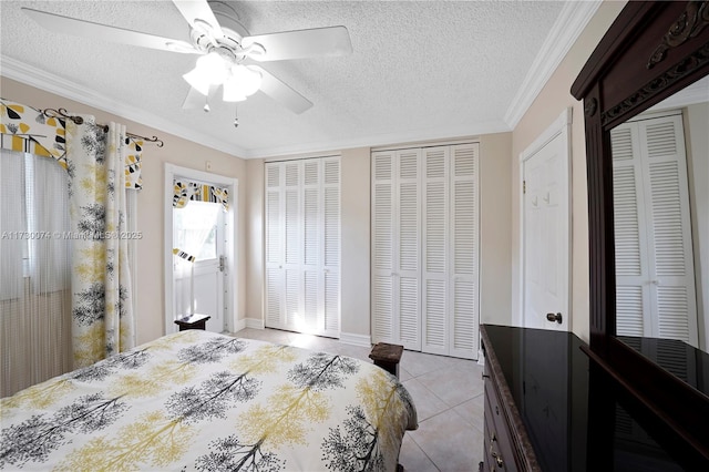 bedroom with light tile patterned floors, two closets, ceiling fan, and crown molding