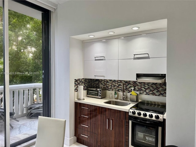 kitchen with sink, backsplash, range, and dark brown cabinetry