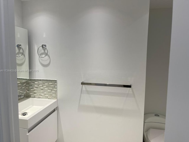 bathroom with vanity, toilet, and tasteful backsplash