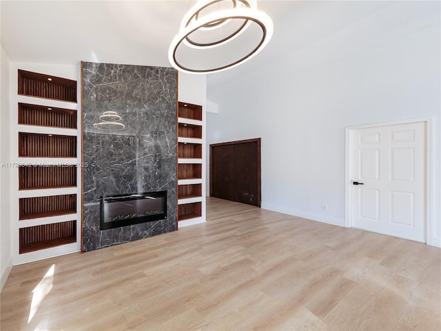 unfurnished living room with built in features, light hardwood / wood-style flooring, and a fireplace