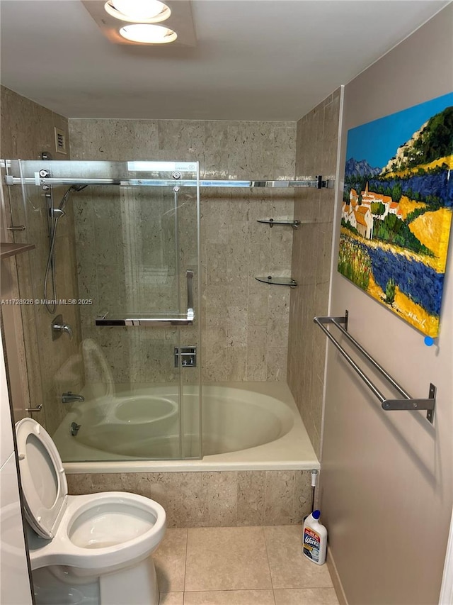 bathroom featuring tile patterned flooring, toilet, and tiled shower / bath