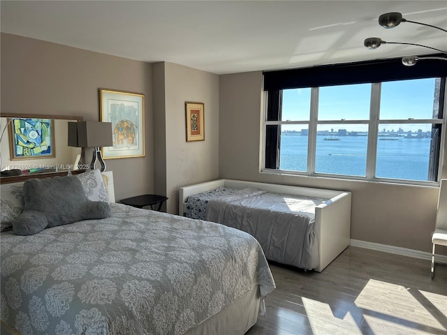 bedroom with a water view and hardwood / wood-style floors