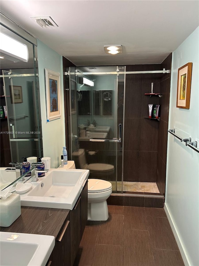 bathroom featuring vanity, a shower with door, and toilet