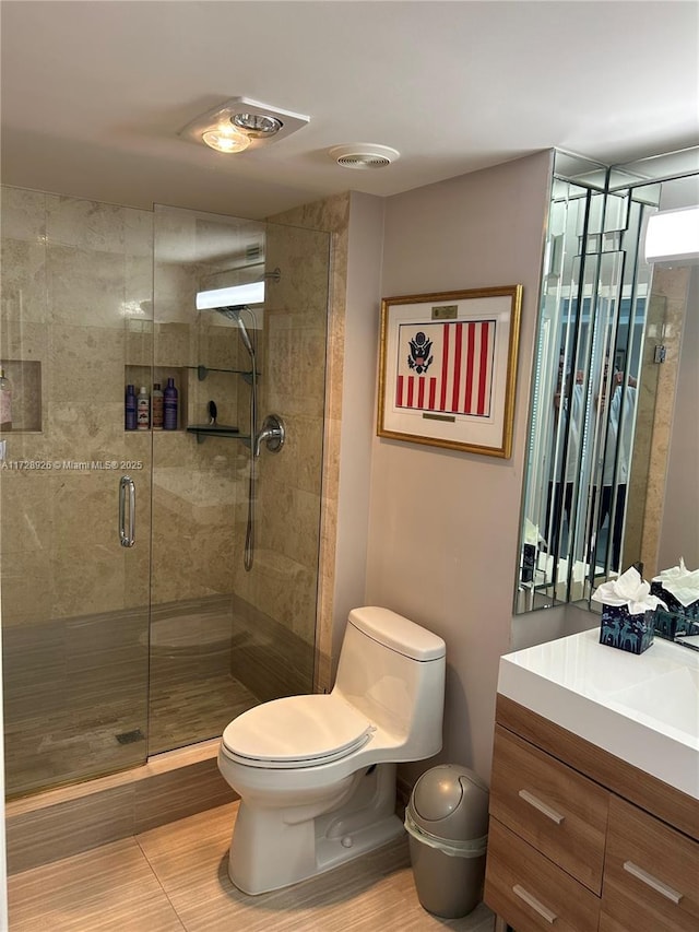 bathroom featuring vanity, a shower with shower door, and toilet