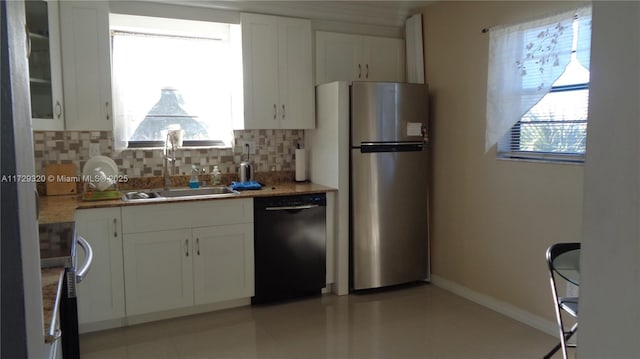 kitchen featuring white cabinetry, black dishwasher, decorative backsplash, sink, and stainless steel refrigerator