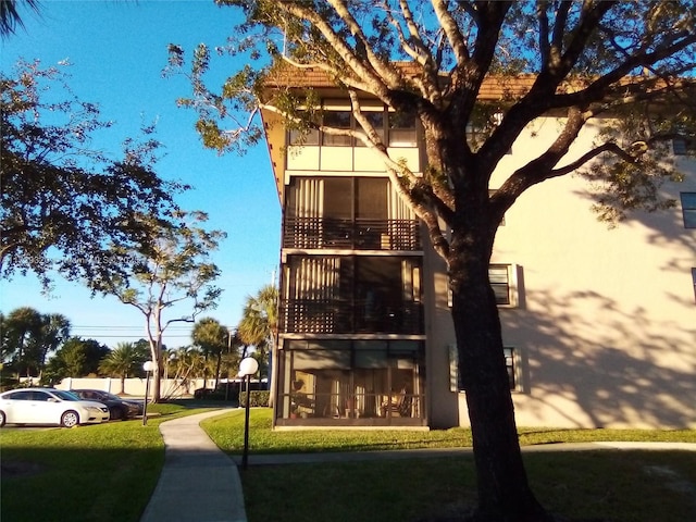 back of property featuring a balcony and a yard