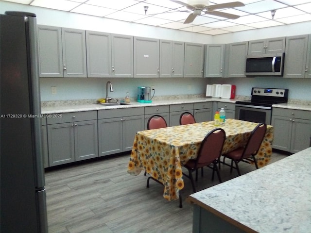 kitchen with sink, stainless steel appliances, light hardwood / wood-style floors, and gray cabinetry