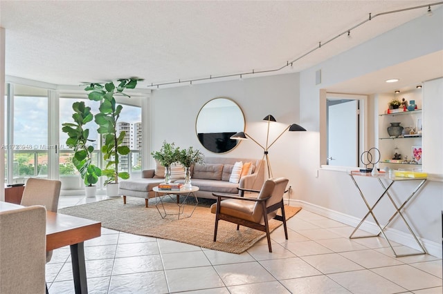 living area featuring rail lighting, a textured ceiling, baseboards, and light tile patterned floors