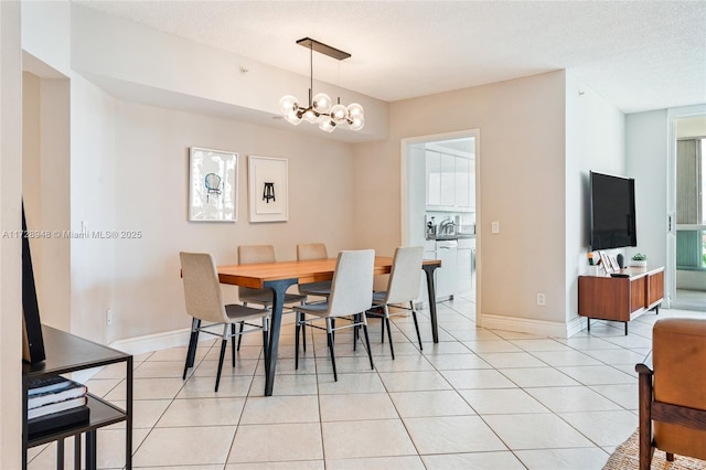 dining room with a notable chandelier, baseboards, a textured ceiling, and light tile patterned flooring