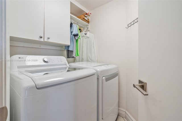 laundry area featuring washer and dryer, cabinet space, and baseboards