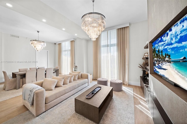 living room featuring a notable chandelier, light wood-type flooring, and a wealth of natural light