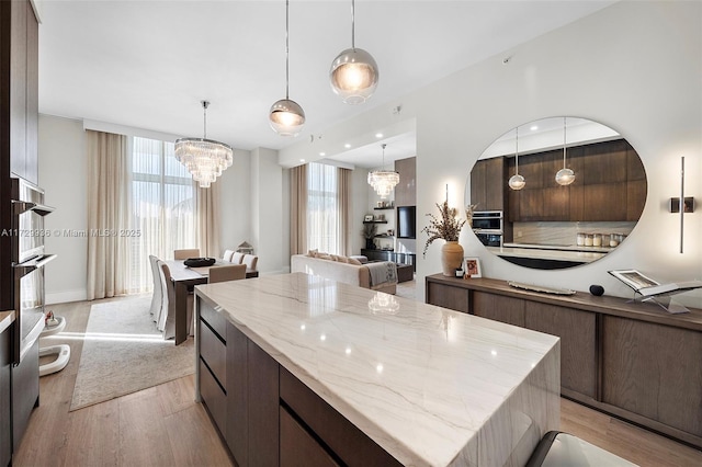 kitchen with light hardwood / wood-style floors, hanging light fixtures, a chandelier, and a healthy amount of sunlight