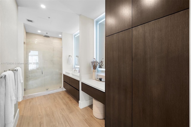 bathroom featuring wood-type flooring, a shower with door, and vanity