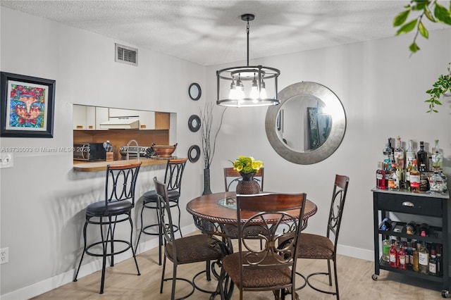 dining area featuring a notable chandelier, a textured ceiling, and light hardwood / wood-style floors