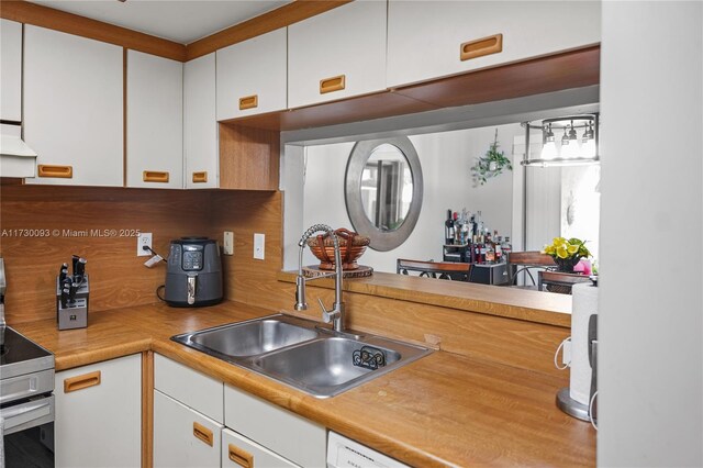 kitchen featuring sink, white cabinets, and electric range