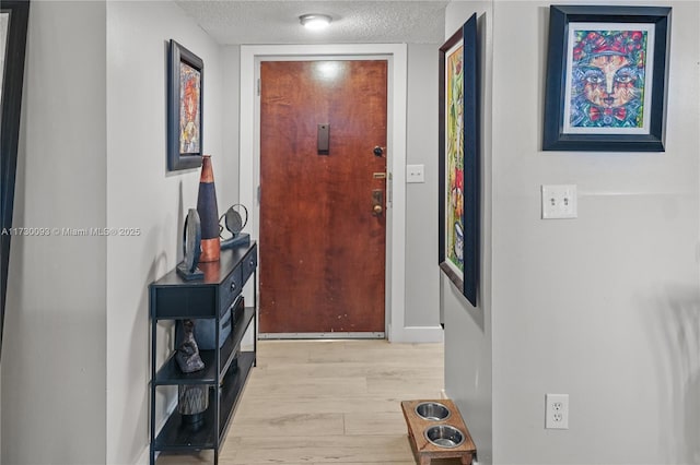 corridor featuring a textured ceiling and light hardwood / wood-style flooring