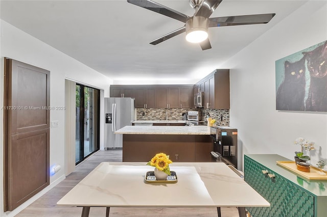 kitchen with light hardwood / wood-style flooring, ceiling fan, appliances with stainless steel finishes, decorative backsplash, and dark brown cabinetry