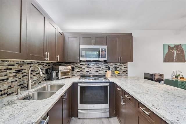 kitchen featuring light stone counters, sink, backsplash, and appliances with stainless steel finishes