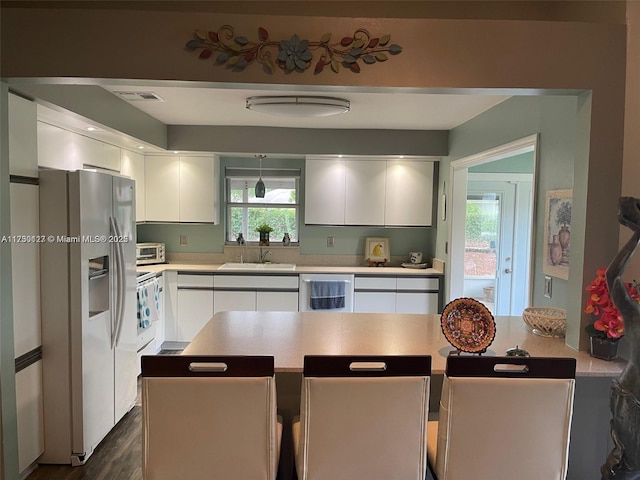 kitchen with dishwasher, white refrigerator with ice dispenser, sink, white cabinetry, and dark hardwood / wood-style floors