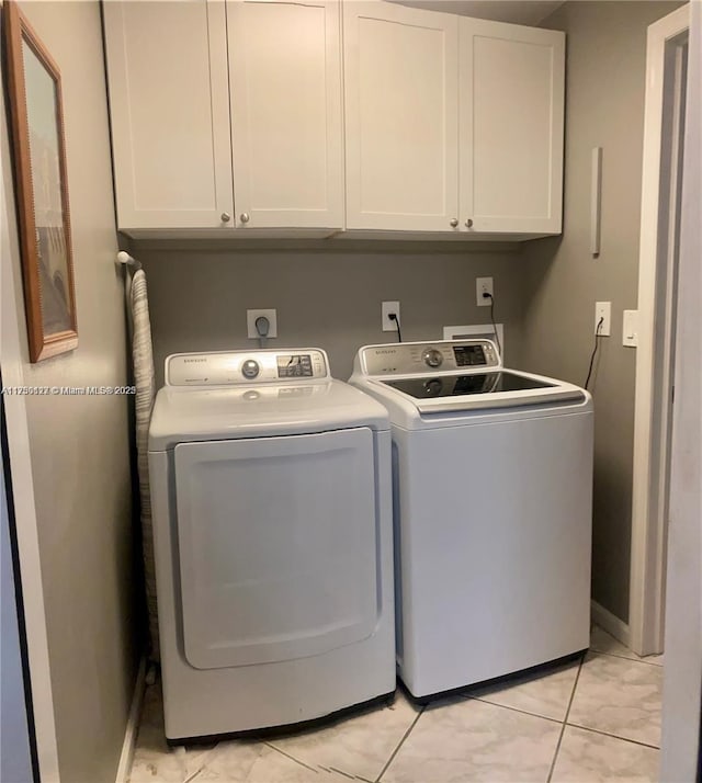 laundry room featuring cabinets, light tile patterned floors, and washing machine and dryer