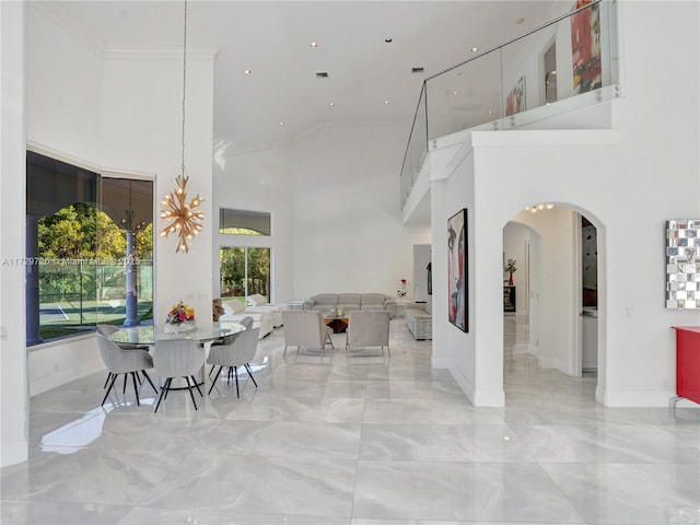 dining room with a notable chandelier, ornamental molding, and a high ceiling