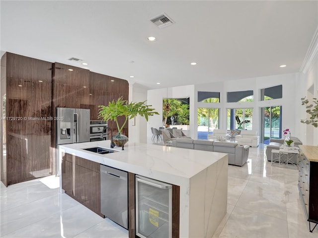 kitchen featuring light stone counters, stainless steel appliances, beverage cooler, and a center island