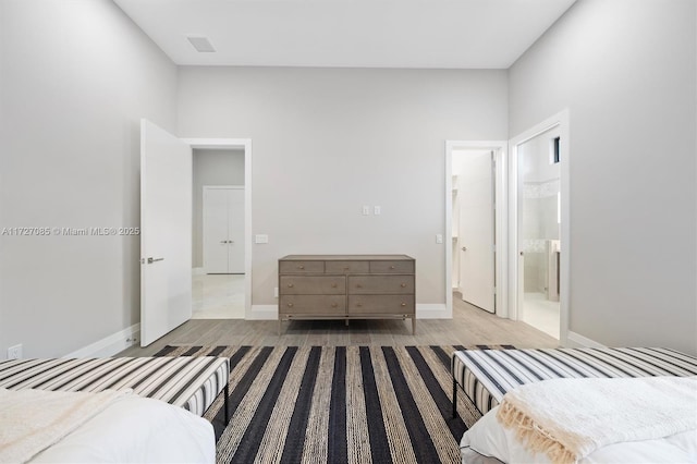 bedroom with light wood-type flooring and ensuite bathroom