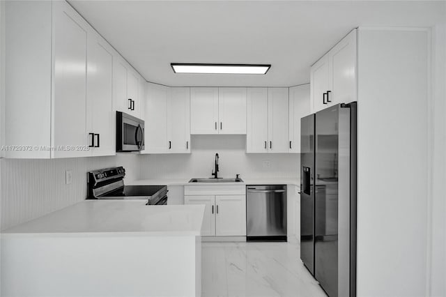 kitchen with white cabinetry, sink, stainless steel appliances, and kitchen peninsula