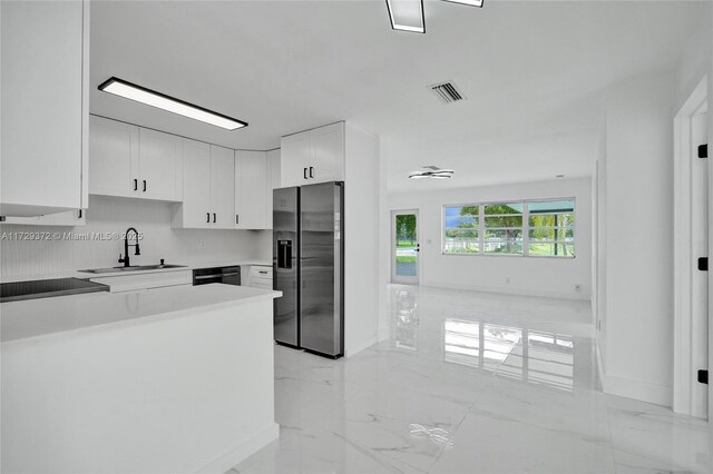 kitchen with stainless steel appliances, white cabinetry, sink, and tasteful backsplash