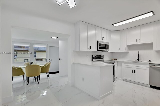 kitchen featuring dishwasher, sink, white cabinets, stainless steel fridge, and decorative backsplash