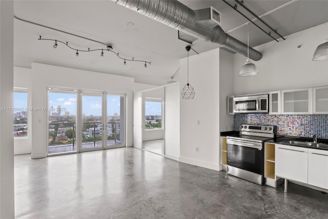 kitchen featuring appliances with stainless steel finishes, white cabinetry, hanging light fixtures, decorative backsplash, and sink