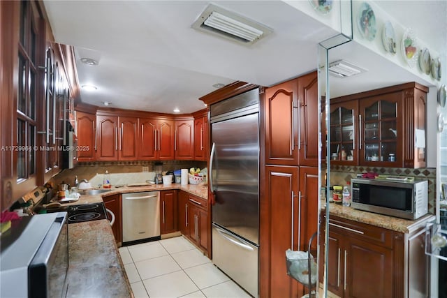 kitchen featuring sink, stainless steel appliances, light stone counters, and light tile patterned flooring